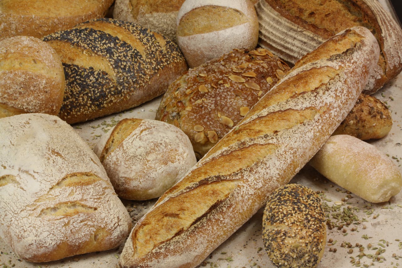 Home A close-up shot of a variety of artisanal breads including baguettes, sourdough, and seeded loaves.