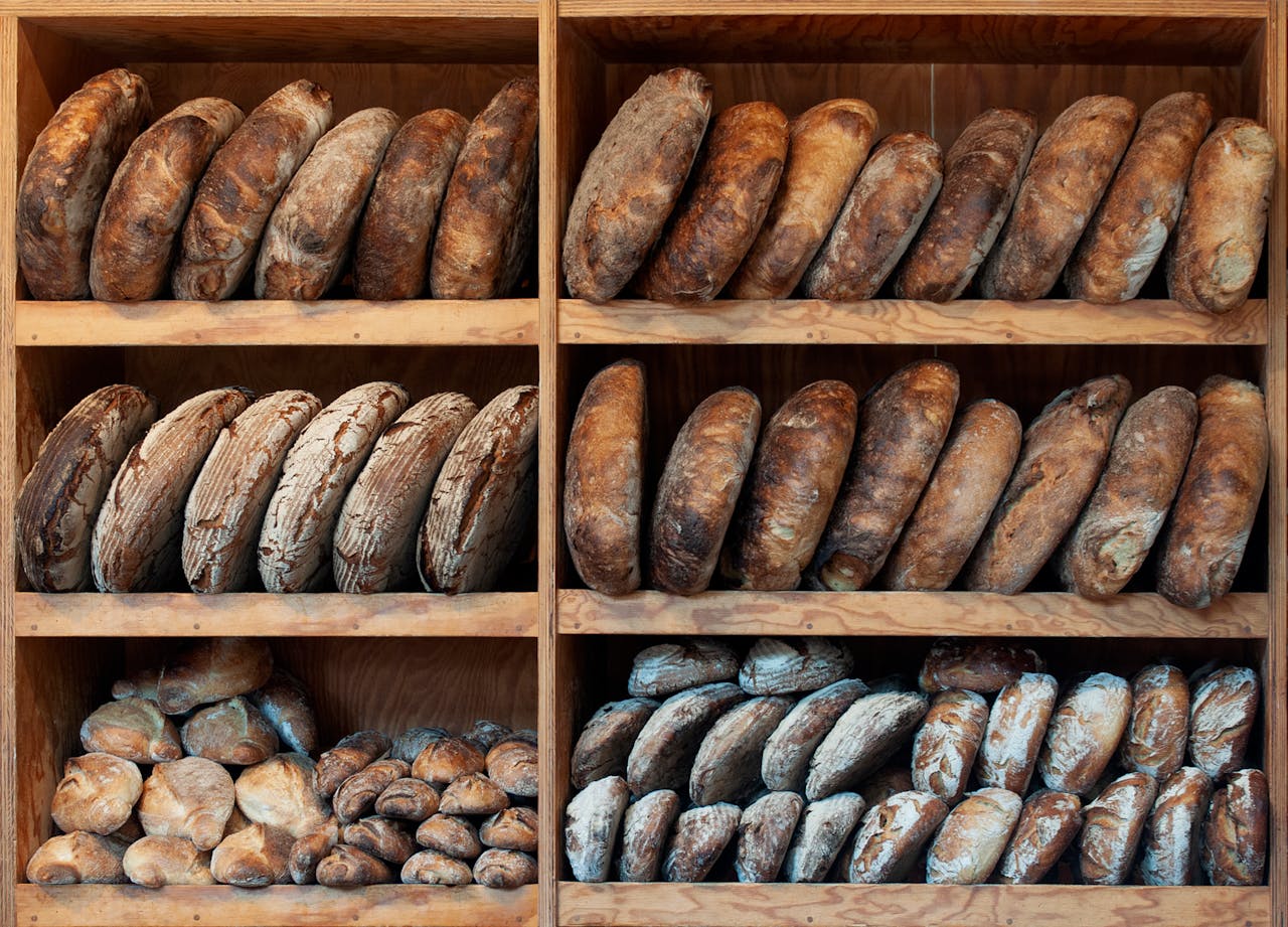 Home A variety of artisanal breads neatly arranged on wooden shelves, creating a rustic display.
