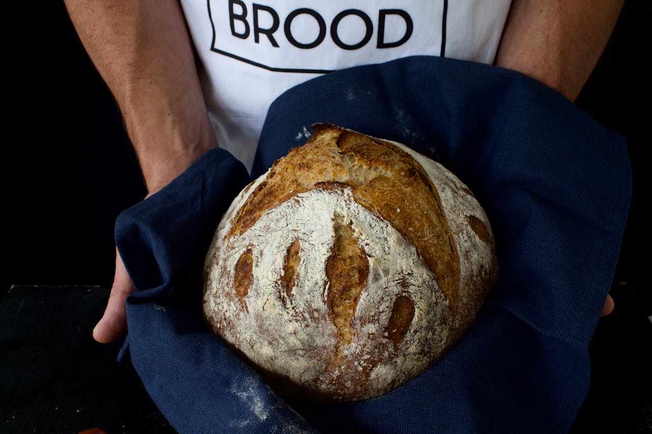 Home Close-up of handmade artisan sourdough bread held in cloth, showcasing rustic texture.